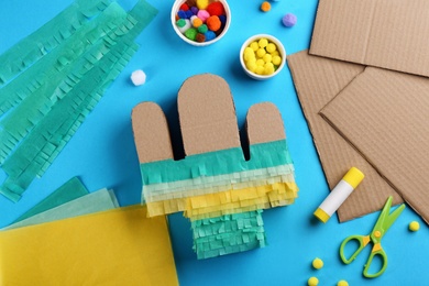 Photo of Cardboard cactus and materials on light blue background, flat lay. Pinata DIY
