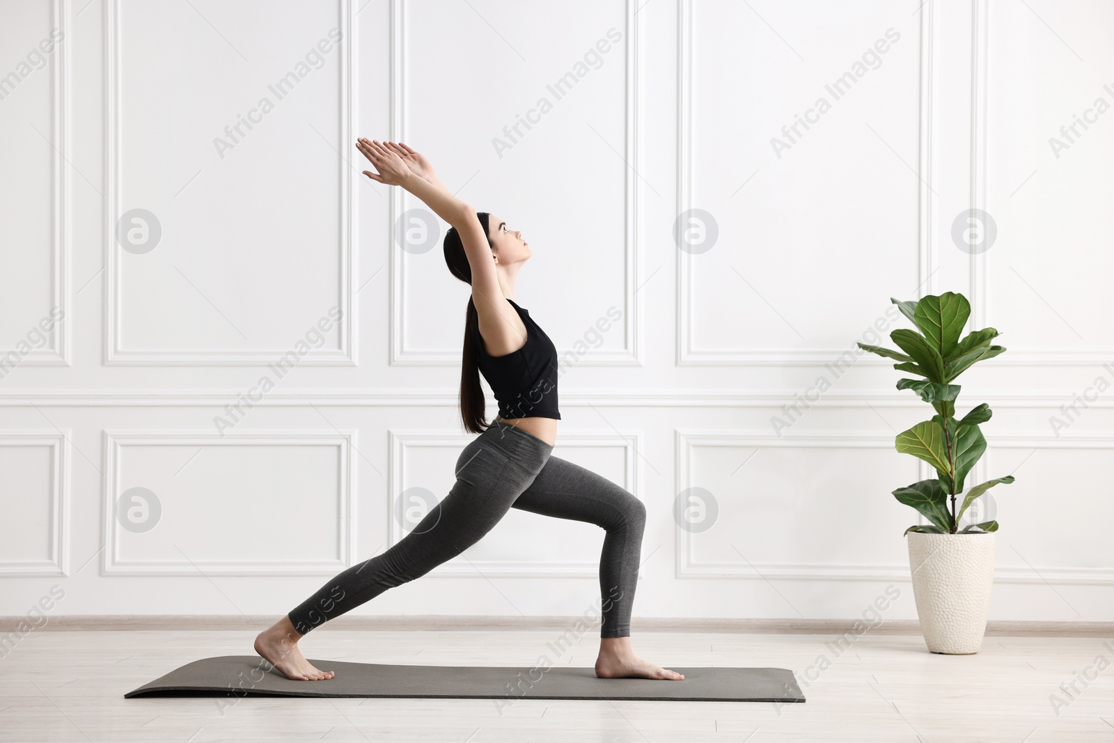 Photo of Girl practicing crescent asana on mat in yoga studio. High lunge pose