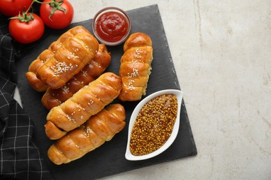 Delicious sausage rolls and ingredients on beige table, flat lay. Space for text