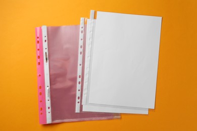 Photo of File folder with punched pockets on orange background, flat lay