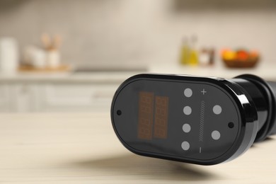 Photo of Thermal immersion circulator on white table in kitchen, closeup with space for text. Sous vide cooking