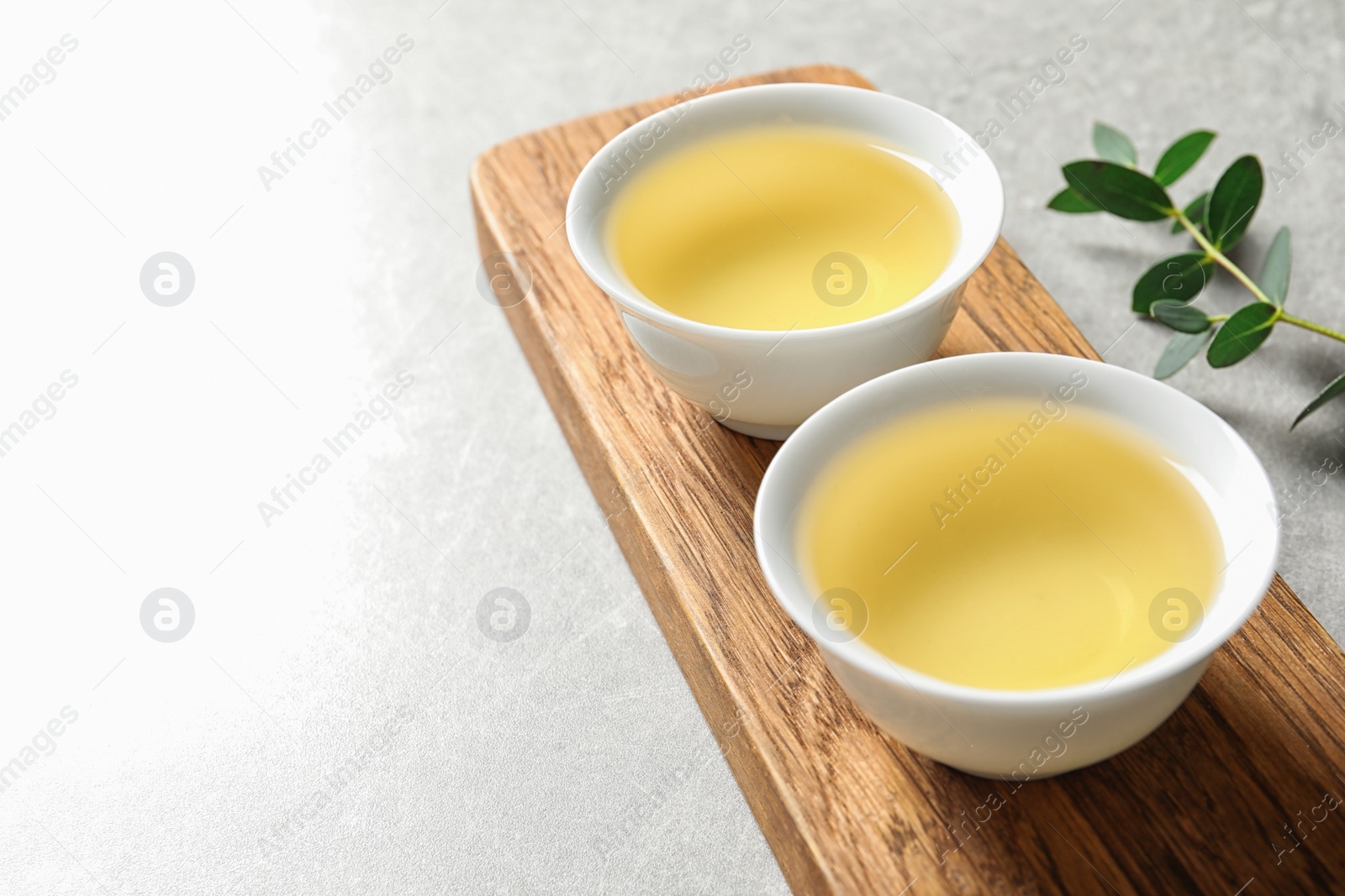 Photo of Stand with cups of freshly brewed oolong tea on table, space for text