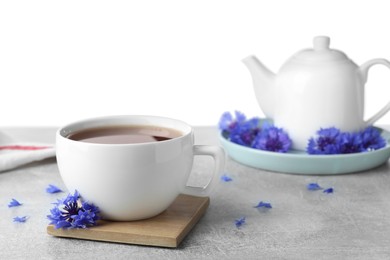 Cornflower tea and fresh flowers on grey table