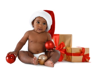 Cute African-American baby wearing Santa hat with Christmas gifts on white background