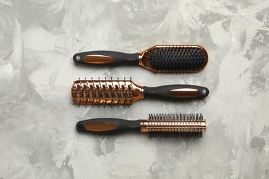 Photo of Set of hair brushes on light grey stone background, flat lay