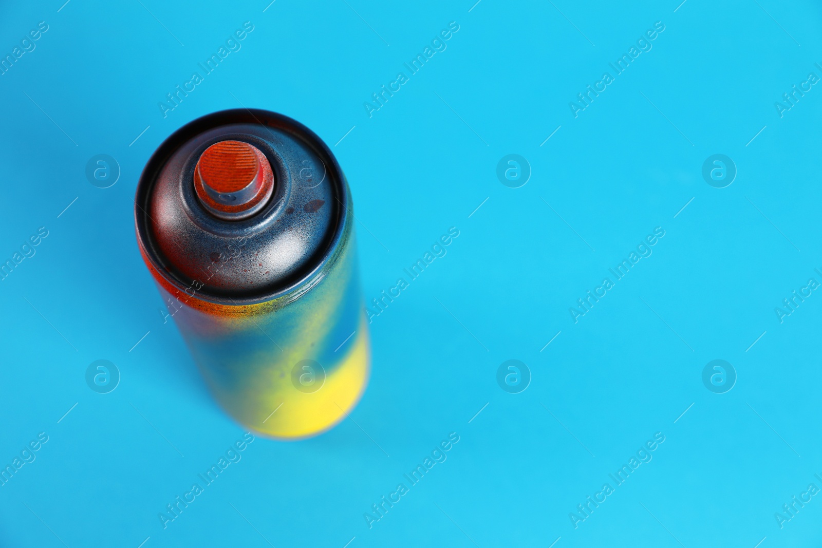 Photo of Used can of spray paint on light blue background. Space for text