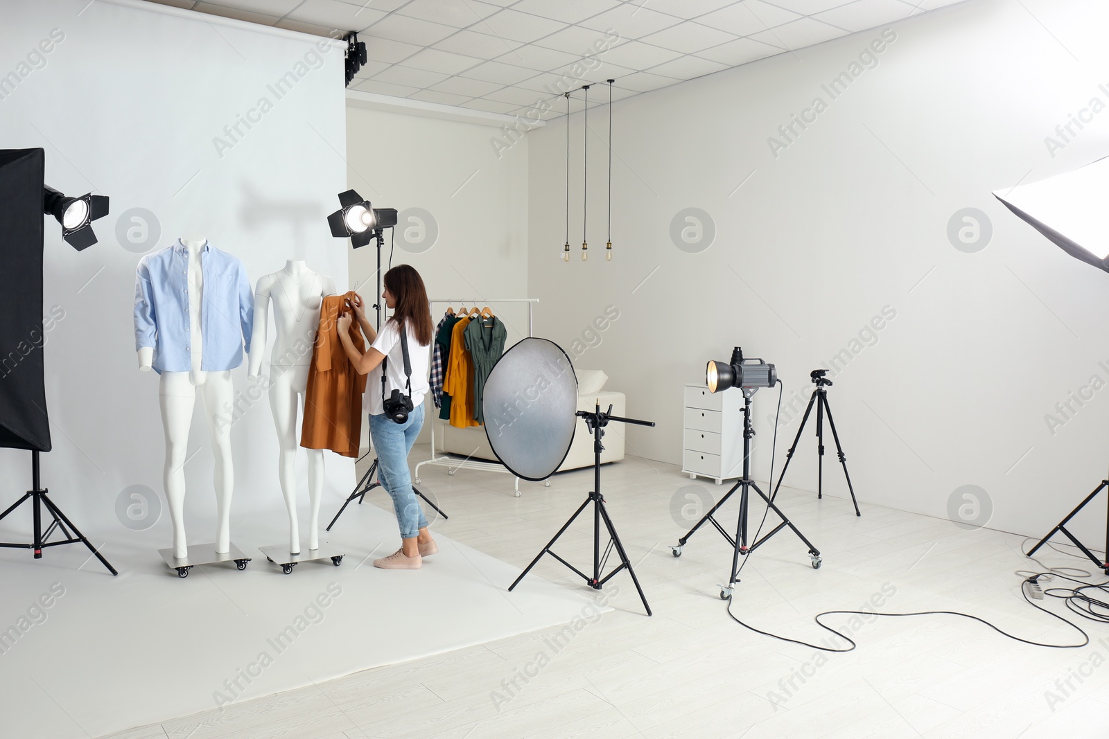 Photo of Woman putting clothes on ghost mannequins in professional photo studio
