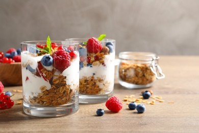 Image of Tasty dessert with yogurt, berries and granola on wooden table