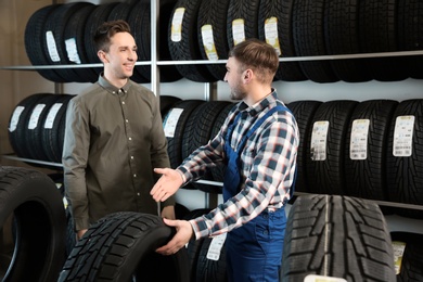 Service center consultant helping customer to choose tire in store