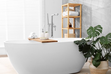 Photo of Different personal care products on bath tub in bathroom