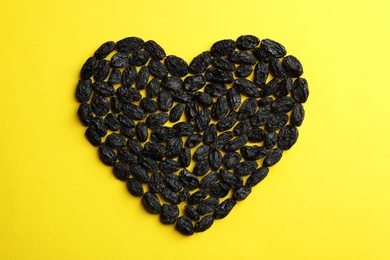 Photo of Heart shape of raisins on color background. Dried fruit as healthy snack