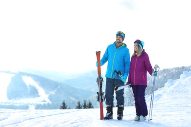 Photo of Happy couple with ski equipment spending winter vacation in mountains. Space for text
