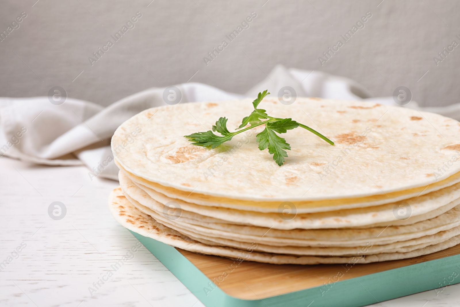 Photo of Wooden board with corn tortillas on table. Unleavened bread