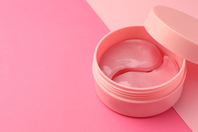 Photo of Jar of under eye patches on pink background, closeup. Space for text