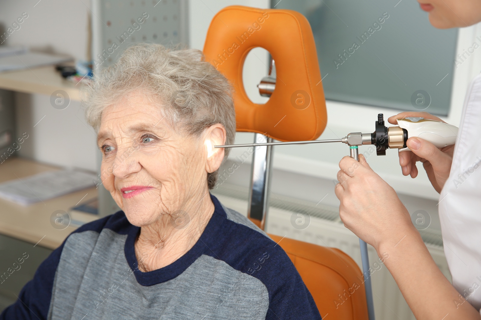 Photo of Professional otolaryngologist examining senior woman with endoscope in clinic. Hearing disorder