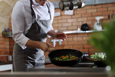Professional chef frying fresh vegetables on stove in restaurant kitchen, closeup