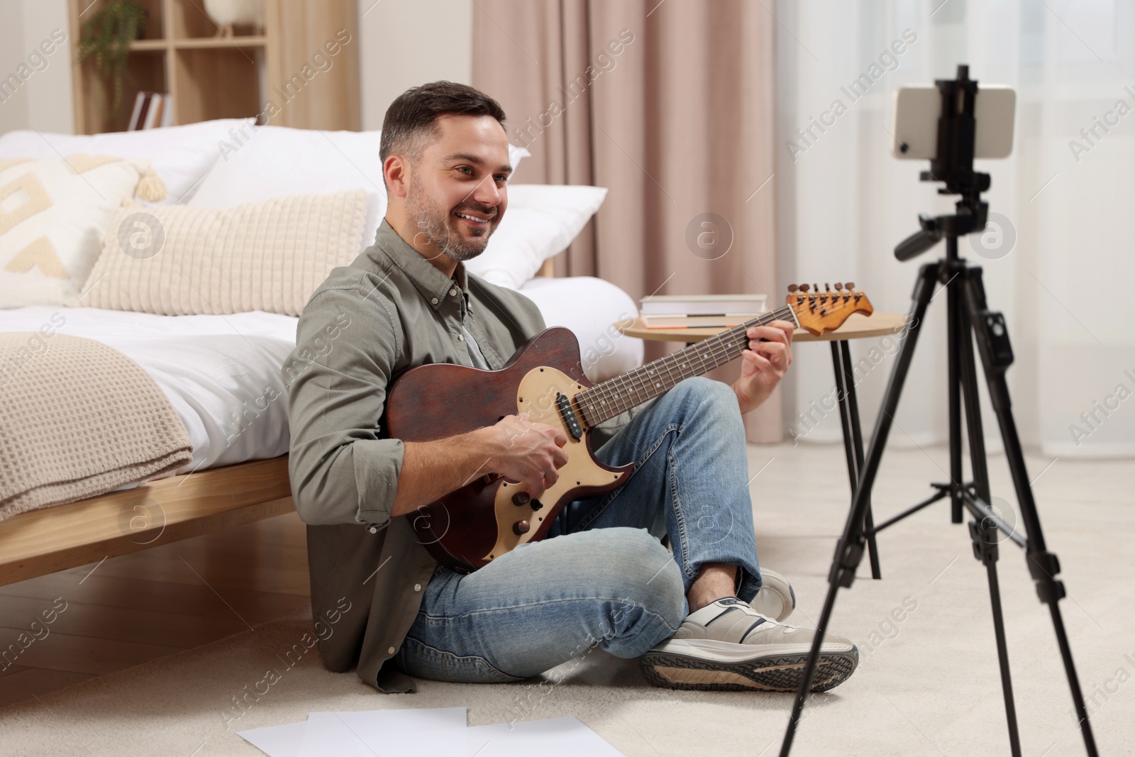 Photo of Music teacher with guitar conducting online lesson at home. Time for hobby