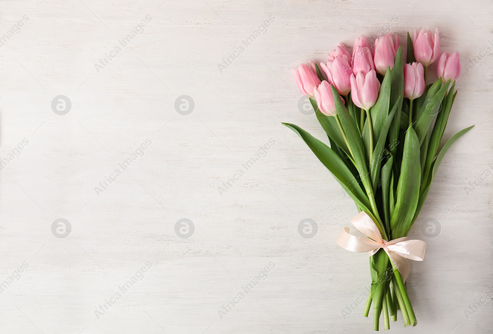 Photo of Beautiful pink spring tulips on white wooden background, top view. Space for text