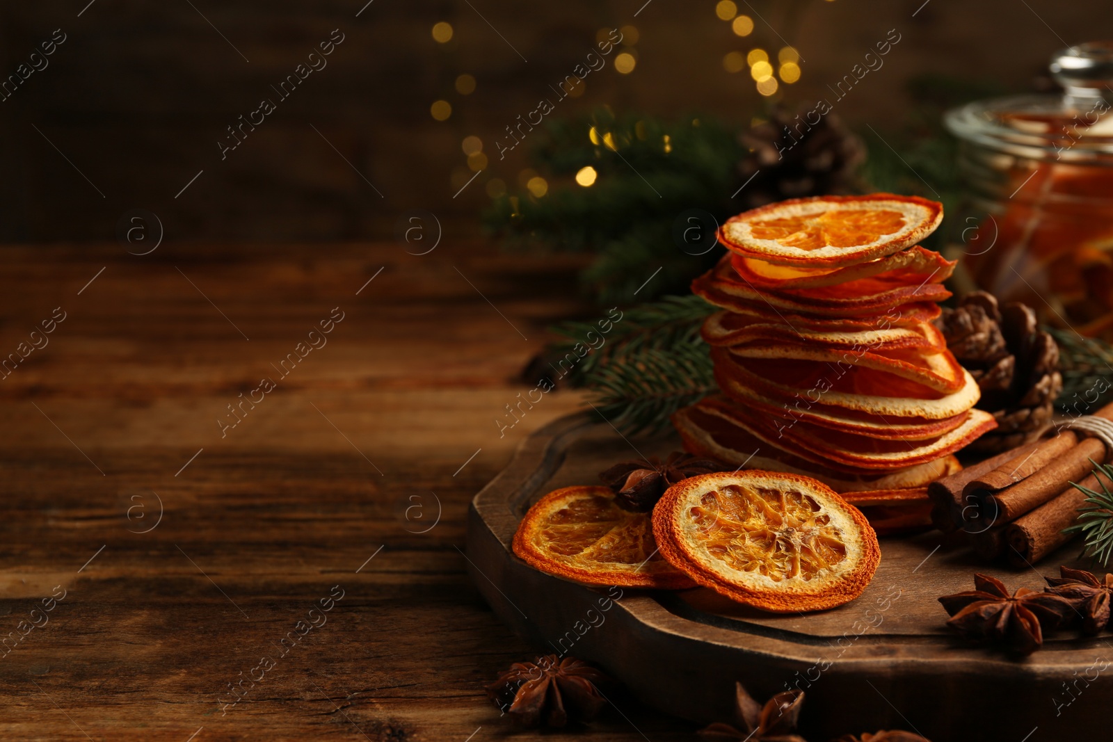 Photo of Dry orange slices, anise stars and cinnamon sticks on wooden table, space for text. Bokeh effect