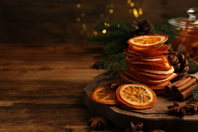 Photo of Dry orange slices, anise stars and cinnamon sticks on wooden table, space for text. Bokeh effect