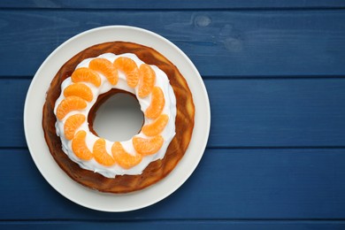 Photo of Homemade yogurt cake with tangerines and cream on blue wooden table, top view. Space for text