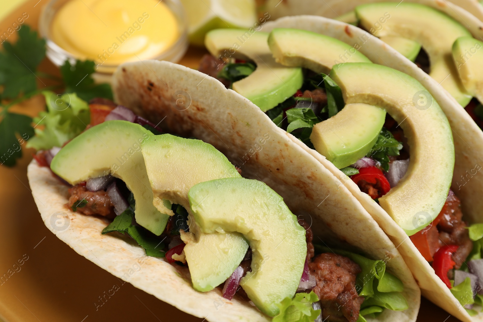 Photo of Delicious tacos with meat, vegetables and avocado on plate, closeup