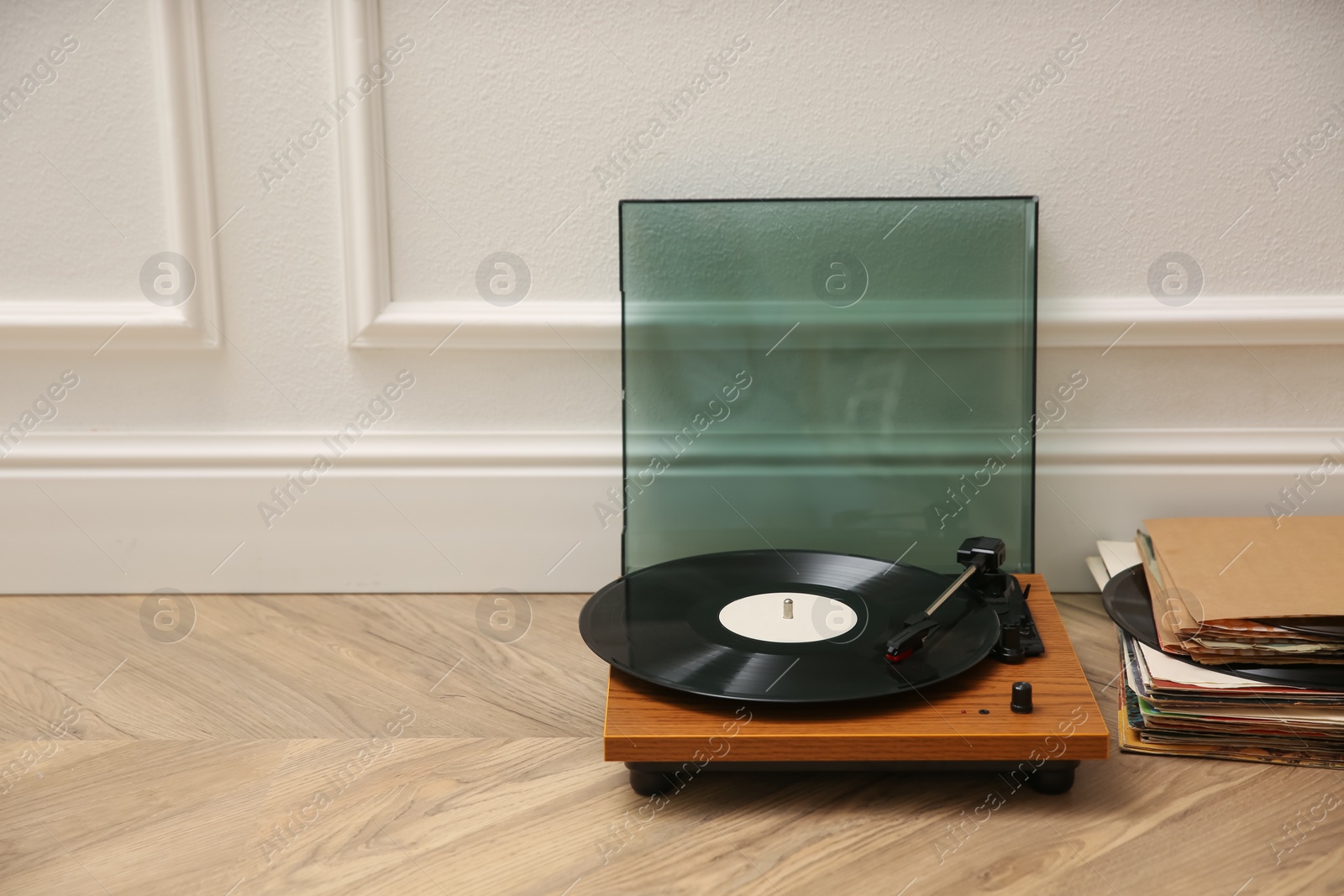 Photo of Stylish turntable and vinyl records on floor indoors, space for text