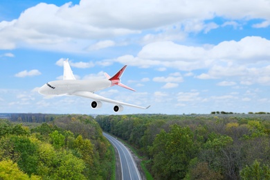 Modern airplane flying in sky over forest