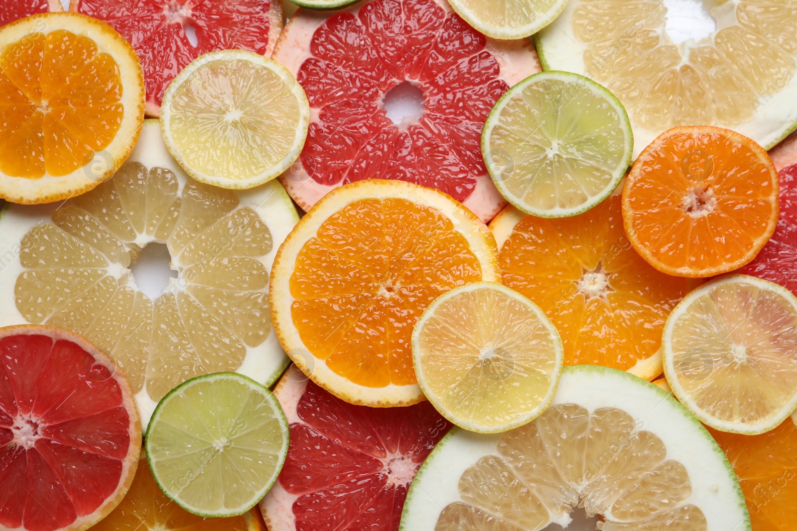 Photo of Slices of different citrus fruits as background, top view