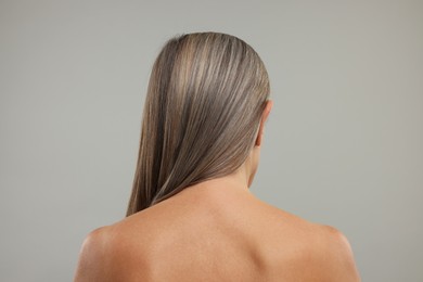 Mature woman with healthy skin on grey background, back view