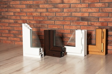 Samples of modern window profiles on floor against brick wall. Installation service