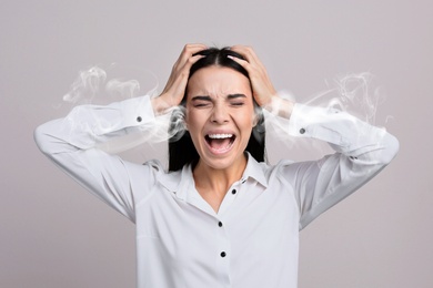 Stressed and upset young woman on light grey background