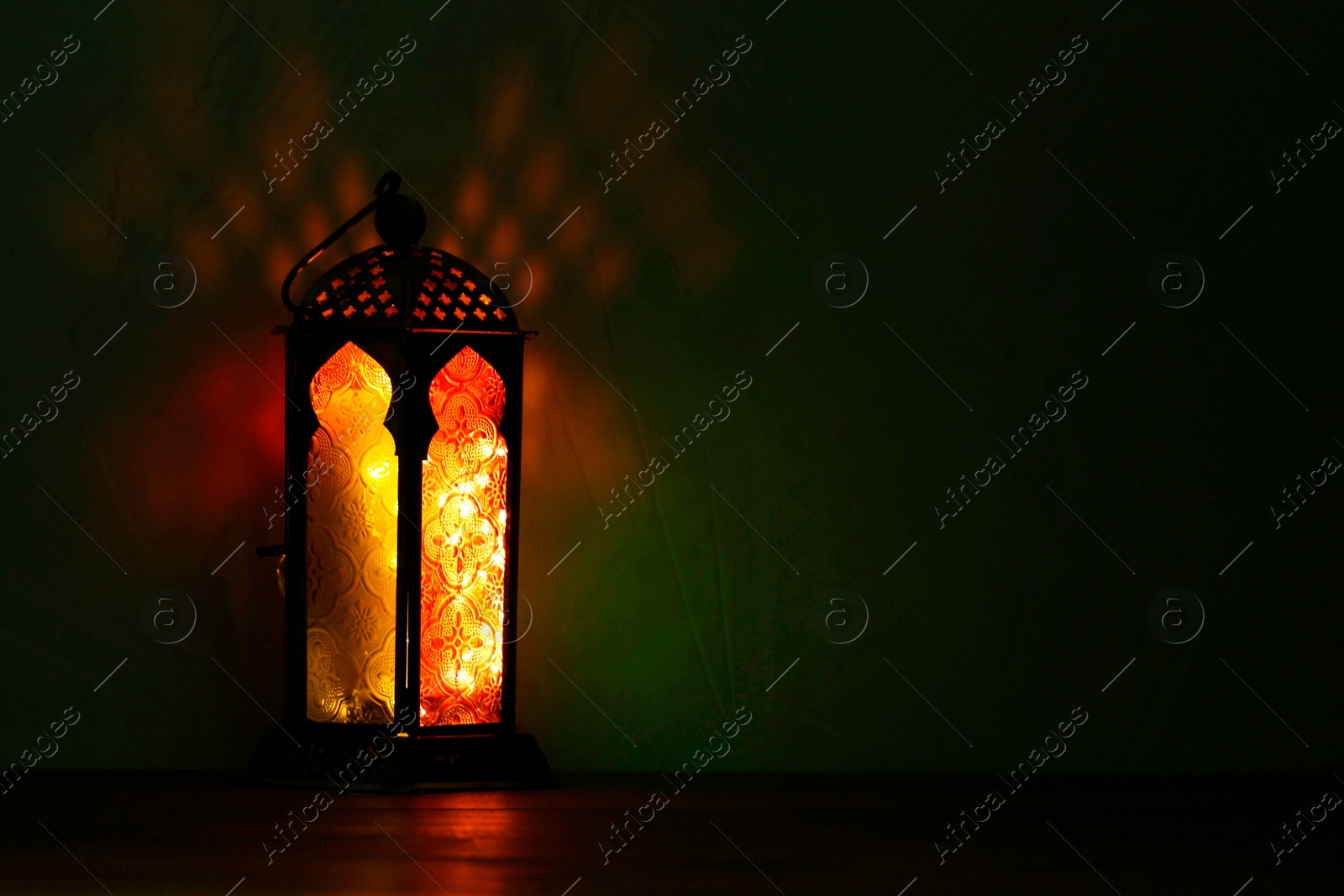 Photo of Decorative Arabic lantern on table against dark background. Space for text