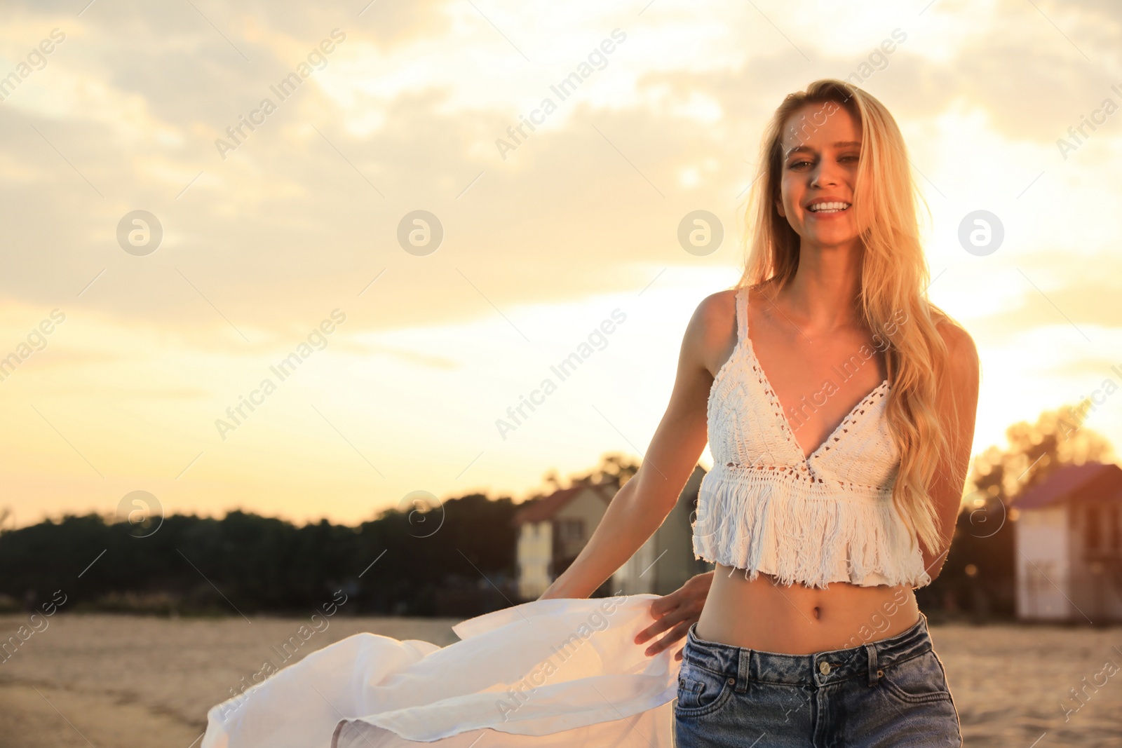 Photo of Beautiful young woman on beach at sunset, space for text