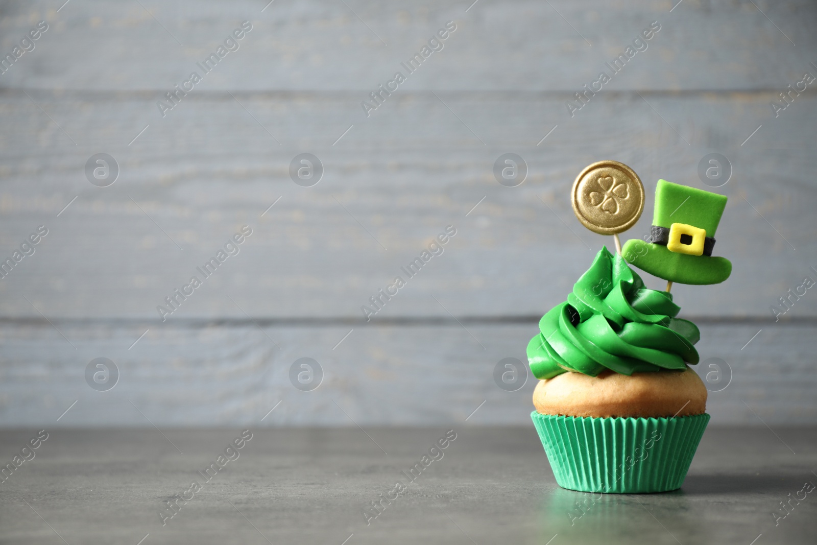 Photo of Decorated cupcake on grey table, space for text. St. Patrick's Day celebration