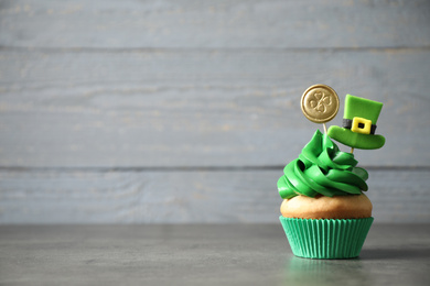 Photo of Decorated cupcake on grey table, space for text. St. Patrick's Day celebration