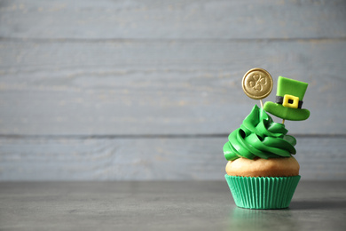 Decorated cupcake on grey table, space for text. St. Patrick's Day celebration