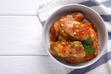 Photo of Delicious stuffed cabbage rolls cooked with homemade tomato sauce on white wooden table, top view. Space for text