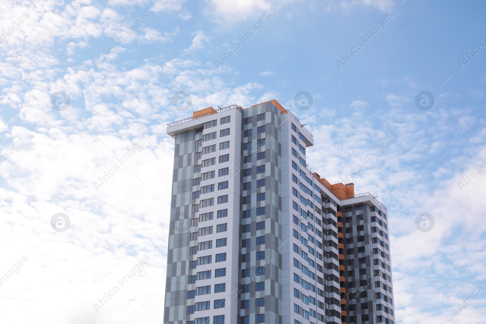 Photo of Building with tinted windows against cloudy sky. Modern architectural design