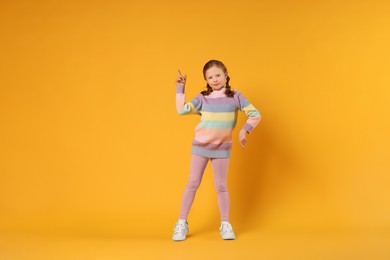 Cute little girl dancing on orange background