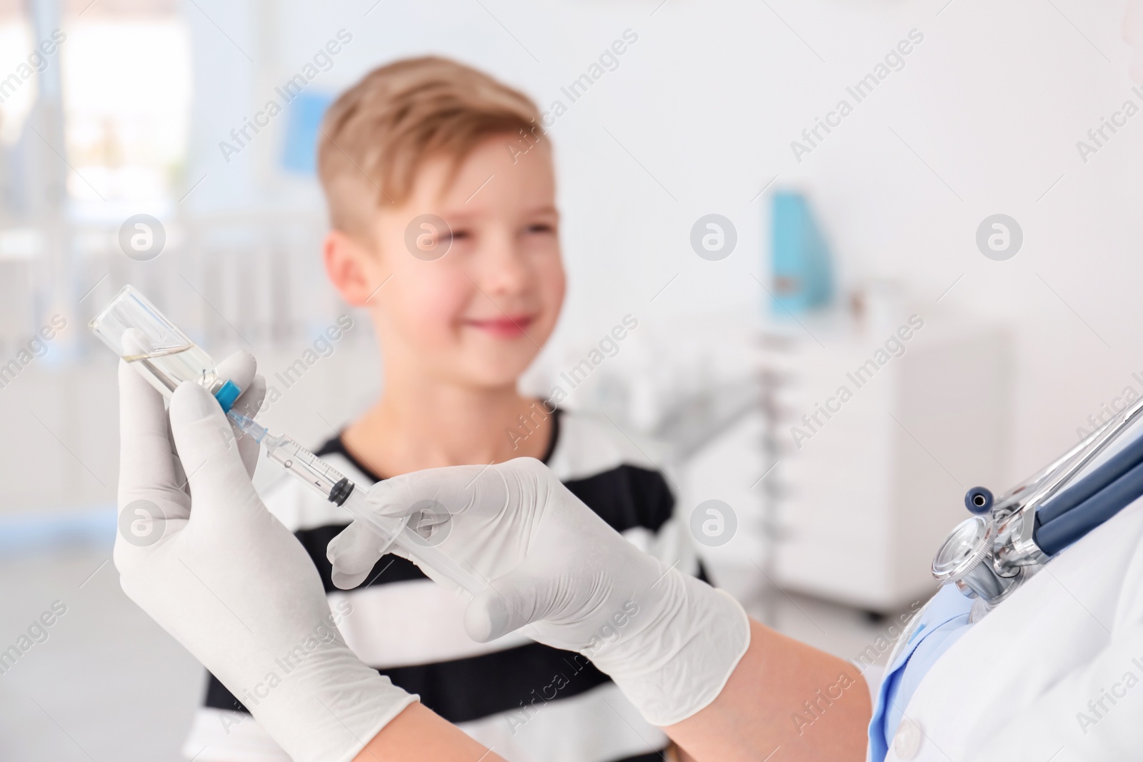 Photo of Doctor filling syringe with medicine and child on background. Vaccination day