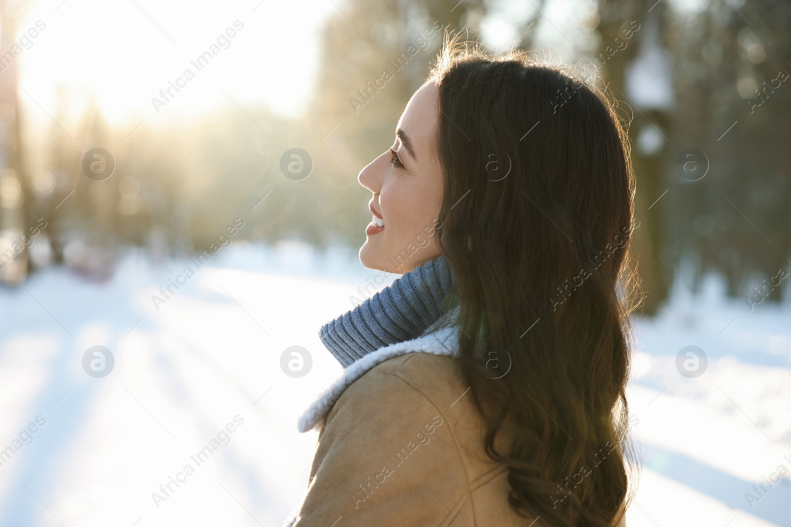 Photo of Portrait of smiling woman in sunny snowy park. Space for text