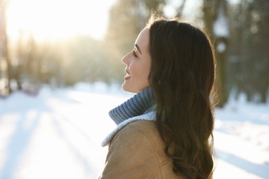 Photo of Portrait of smiling woman in sunny snowy park. Space for text
