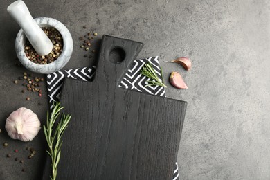 Black cutting board, napkin and spices on grey table, flat lay. Space for text