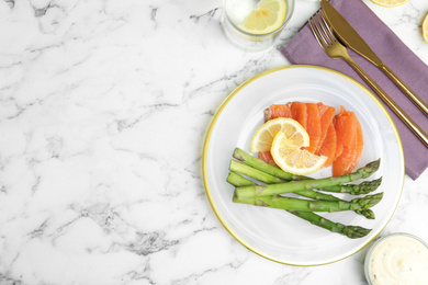 Tasty asparagus with salmon and lemon on white marble table, flat lay. Space for text