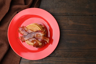 Delicious pancakes with bacon and honey on wooden table, top view. Space for text