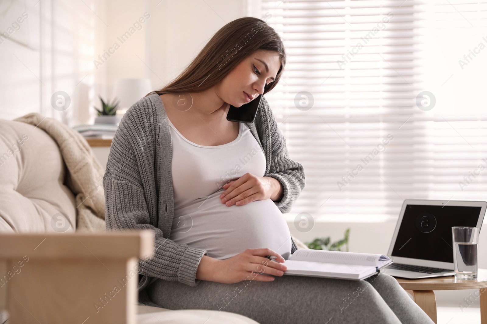 Photo of Pregnant woman working on sofa at home. Maternity leave