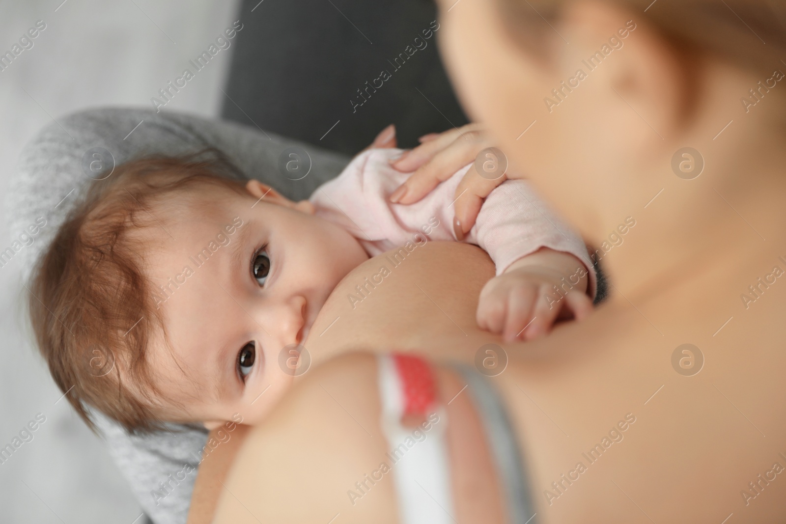 Photo of Young woman breastfeeding her baby at home, closeup