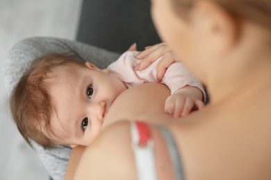 Photo of Young woman breastfeeding her baby at home, closeup