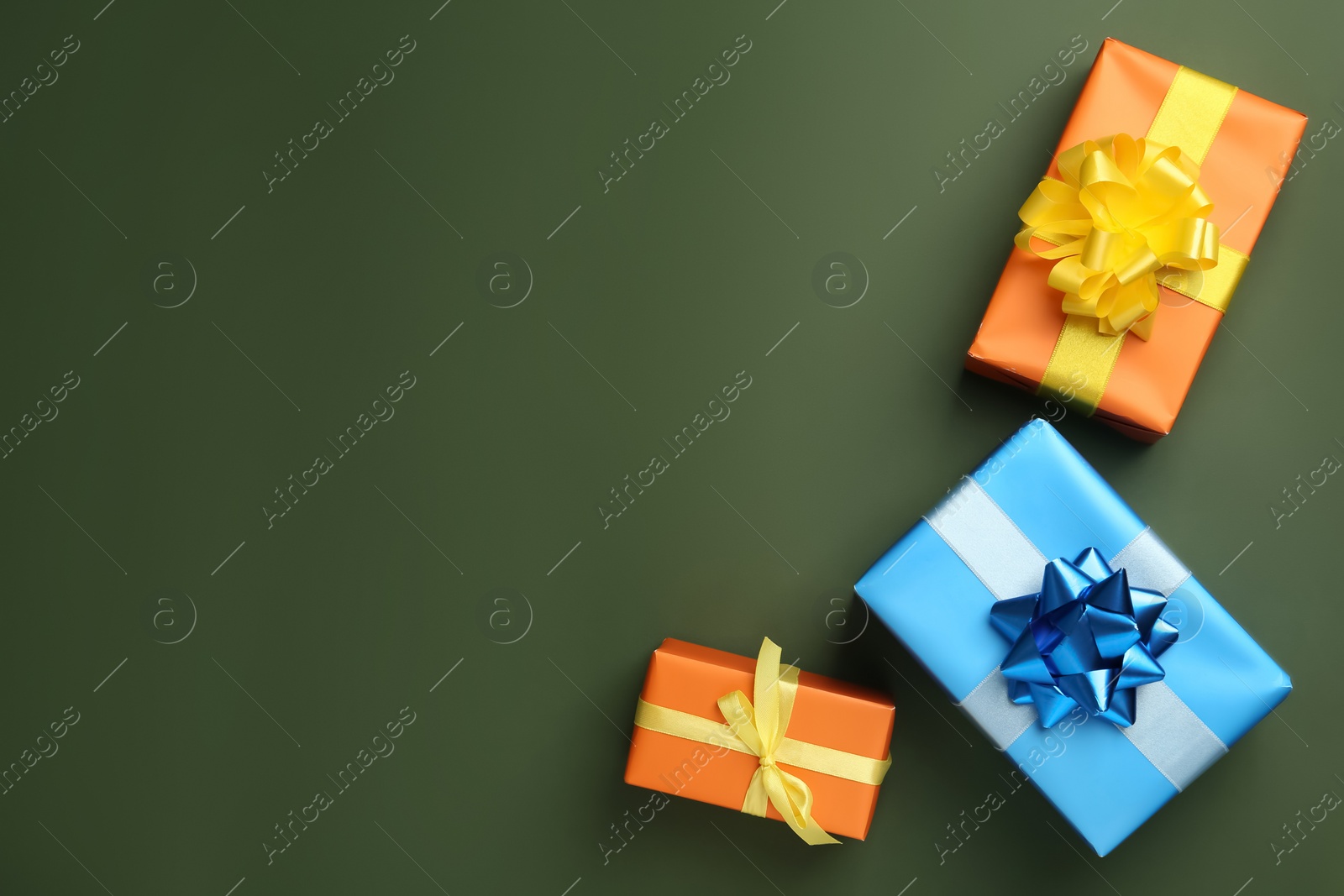 Photo of Colorful gift boxes on dark green background, flat lay. Space for text